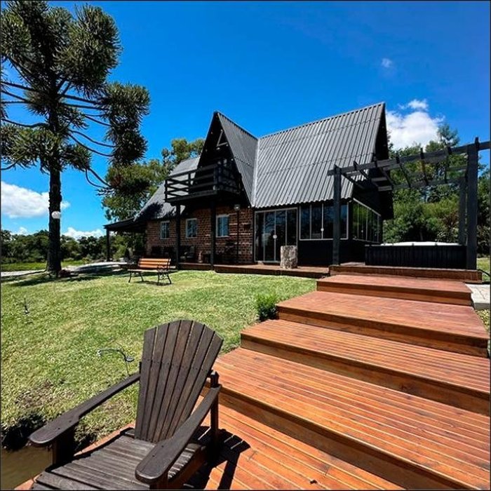 Cabana A-frame de madeira escura entre as árvores da Serra Gaúcha